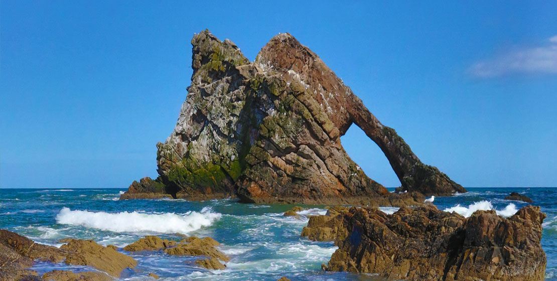 Golden light on the cliffs and sea arch of the Moray coast