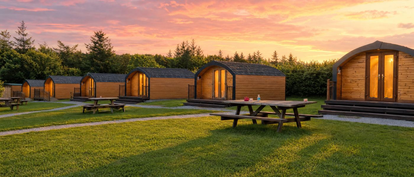Greencraig glamping pods glowing at dusk with the Moray coast beyond