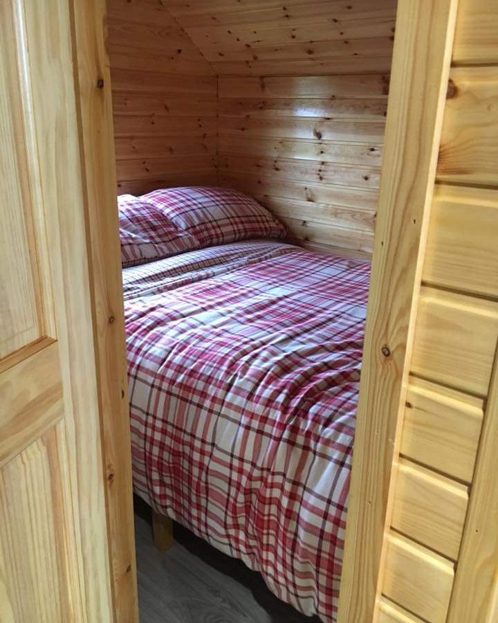 The small double bedroom inside a pod, with pine cladding and a tartan duvet